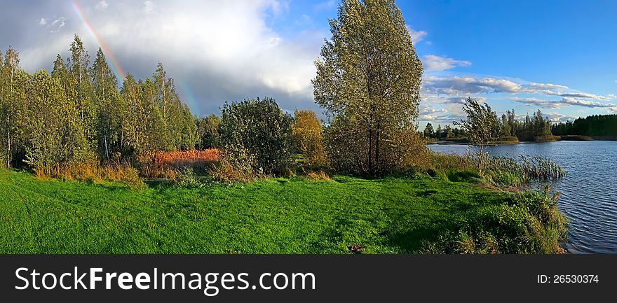 Picturesque autumn landscape with river and bright rainbow over the woodland. Picturesque autumn landscape with river and bright rainbow over the woodland