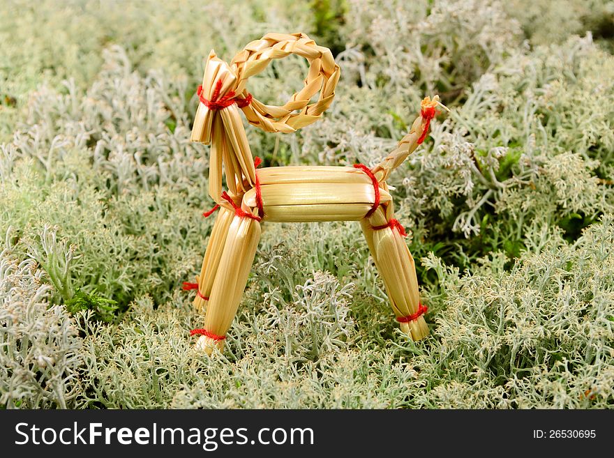 Goat Christmas ornament in straw with background of lichen