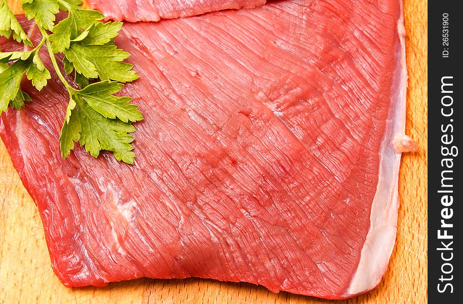 Raw meat slice on board with parsley