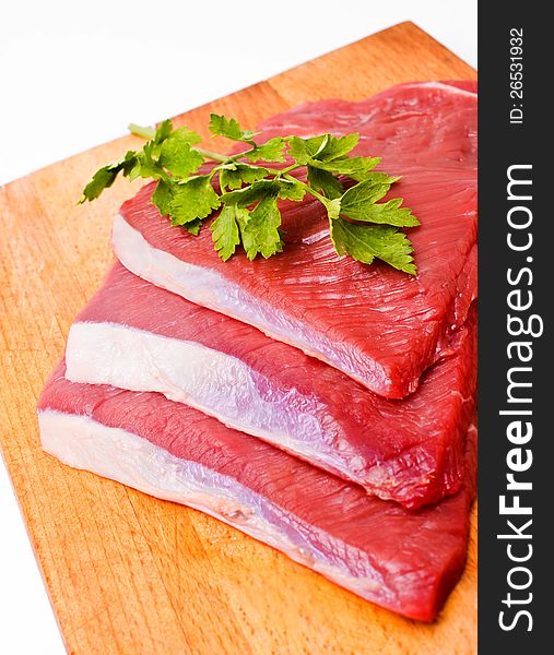 Raw meat slices on board with parsley