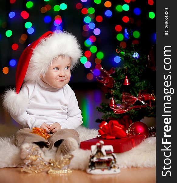 Funny baby in Santa Claus hat on bright festive background. Funny baby in Santa Claus hat on bright festive background