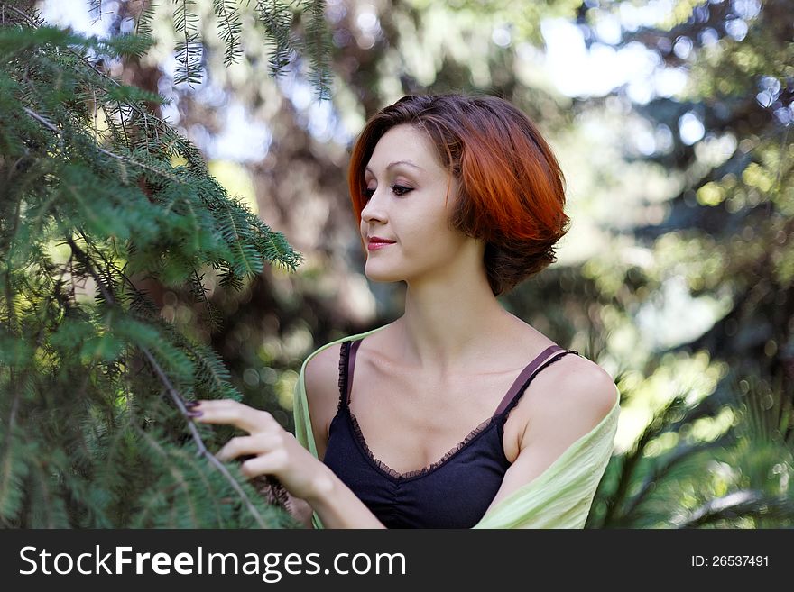Nice redhead girl near a tree on a walk