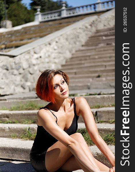 Beautiful redhead girl posing on the stairs