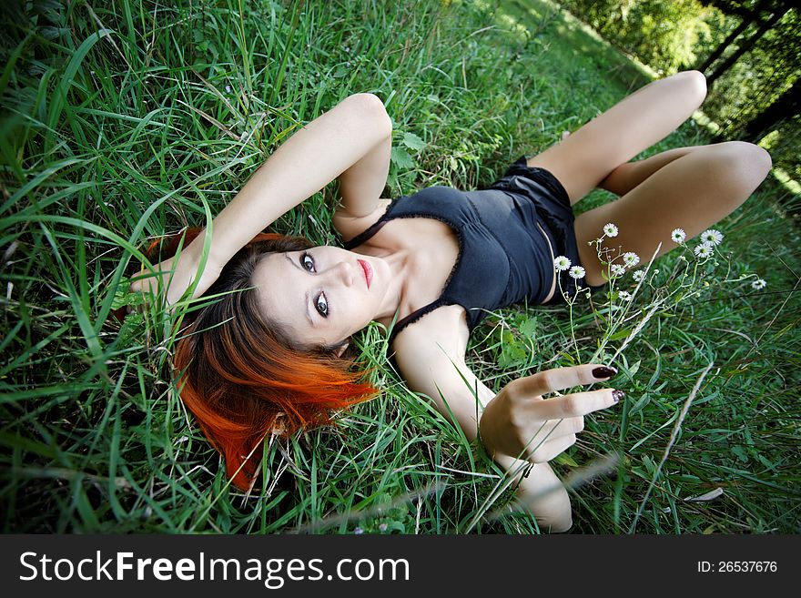 Portrait of pretty redhead girl in the grass in spring