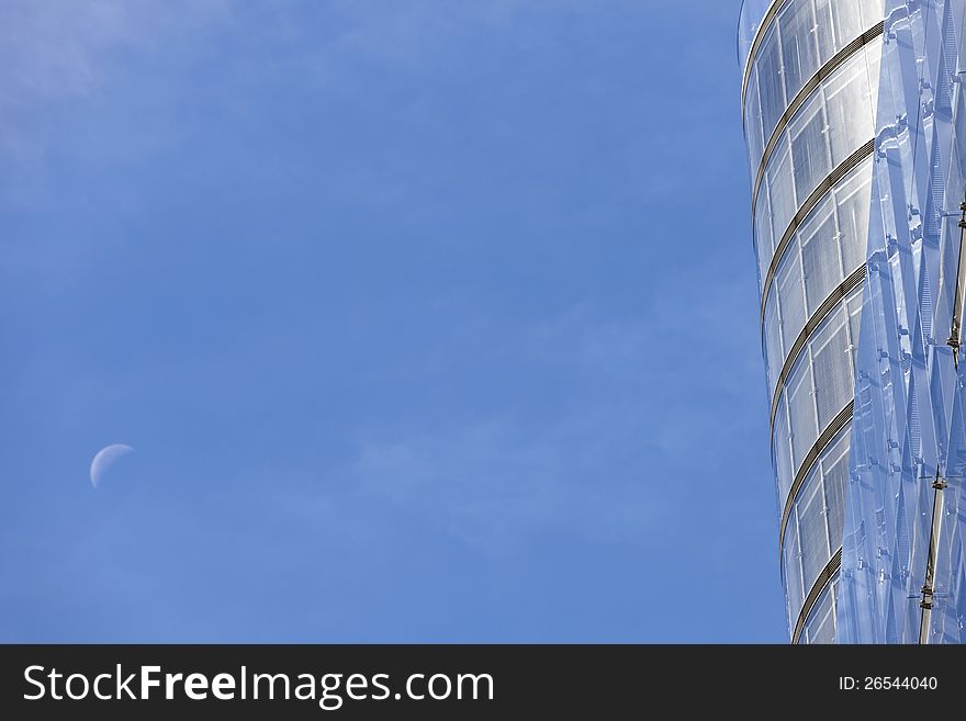 Modern office building with rising moon in abstract composition and much copy space.