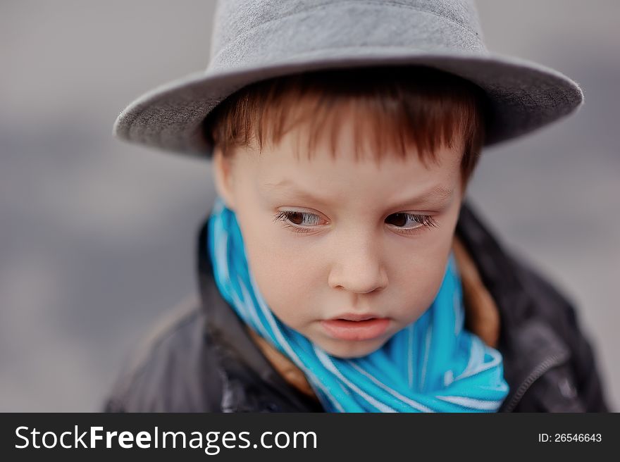 Portrait of a boy in an elegant gray hat and blue scarf. Portrait of a boy in an elegant gray hat and blue scarf