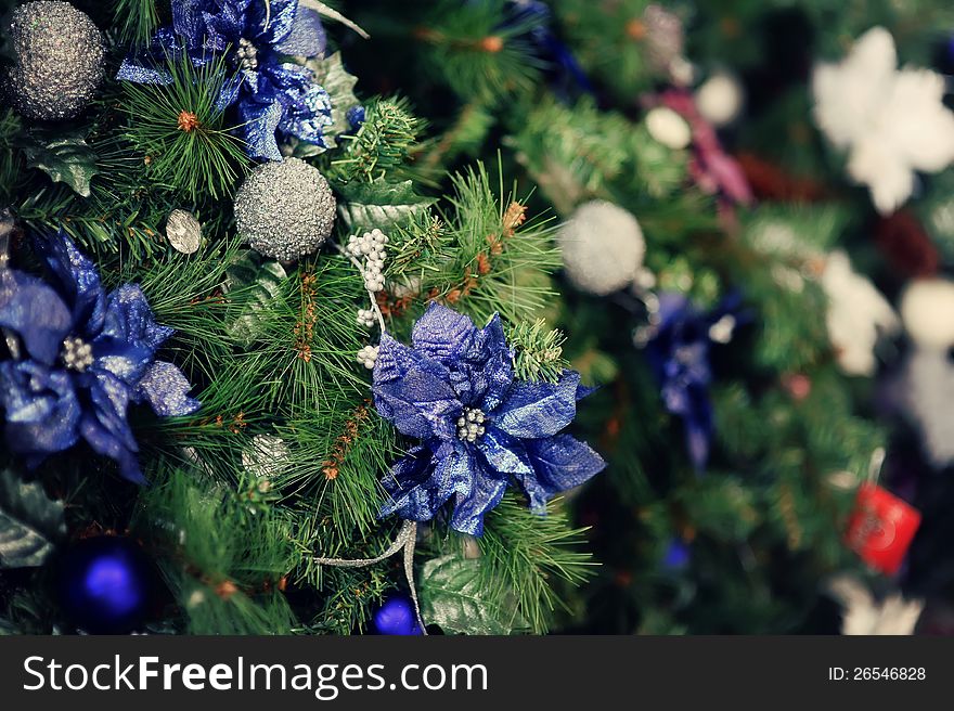 The child decorates a green New Year tree with color toys. The child decorates a green New Year tree with color toys