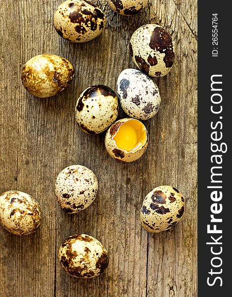 Quail eggs on a wooden table with one egg broken