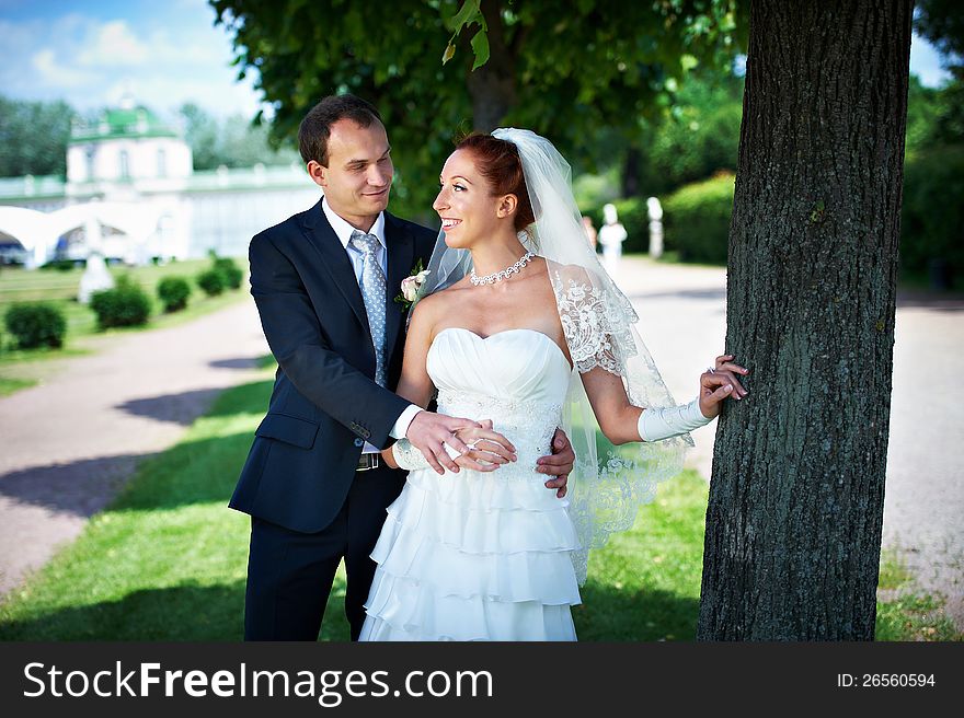 Happy bride and groom about tree on wedding walk