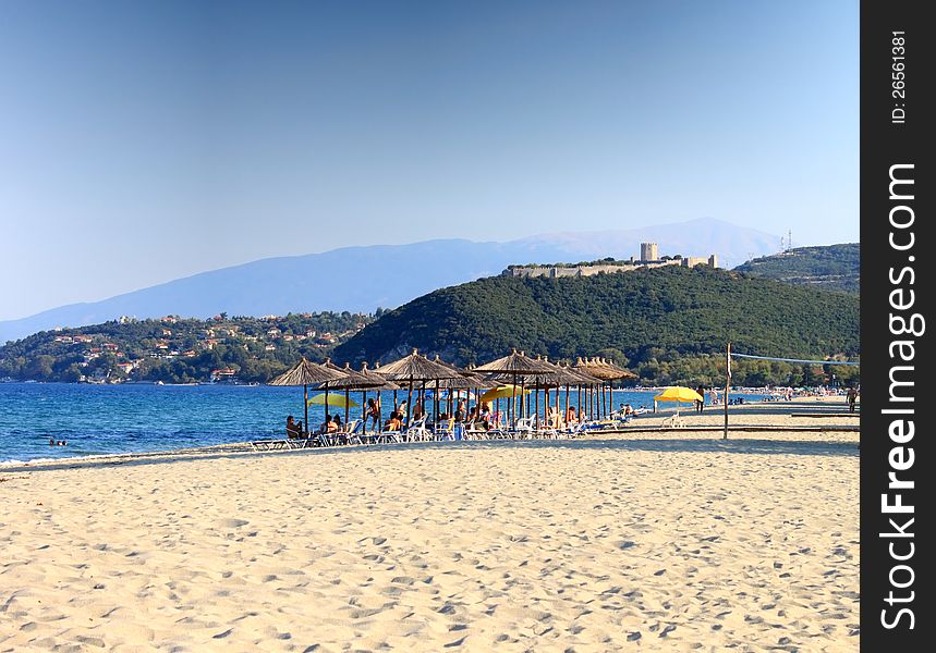 View of the Platamon beach with his golden sand. In the back the famous Platamon Castle. HDR Image. View of the Platamon beach with his golden sand. In the back the famous Platamon Castle. HDR Image