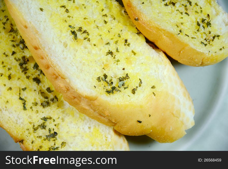 Sliced bread bun spread with butter, garlic and herb. Sliced bread bun spread with butter, garlic and herb.