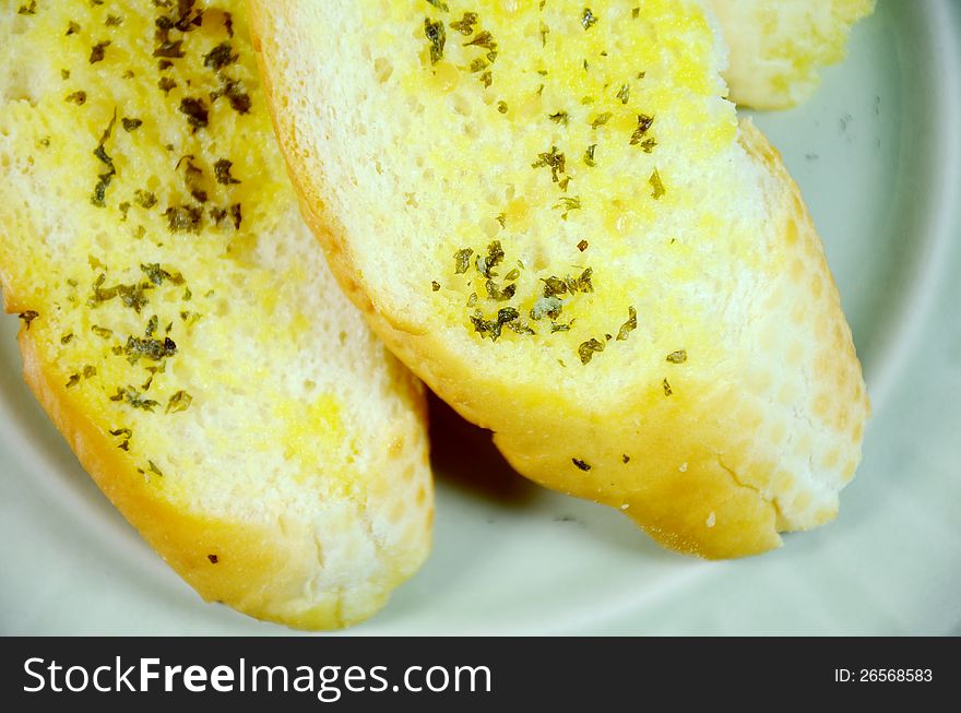 Sliced bread bun spread with butter, garlic and herb. Sliced bread bun spread with butter, garlic and herb.