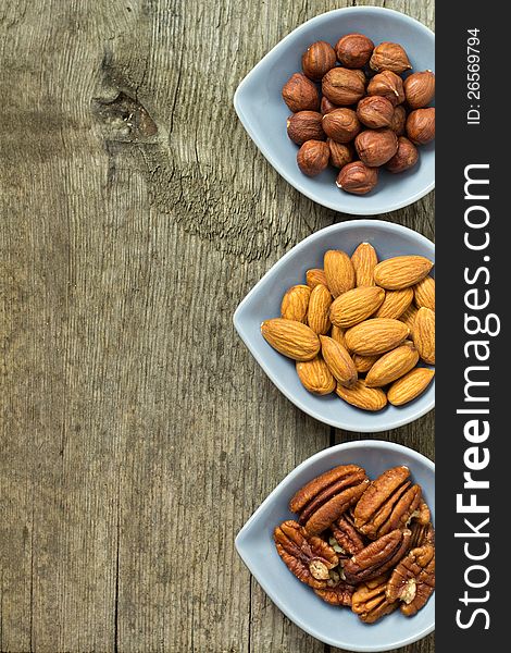 Almonds, hazelnuts and pecans on wooden background