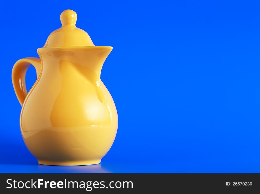 Nice yellow ceramic milk jug on blue background. Nice yellow ceramic milk jug on blue background