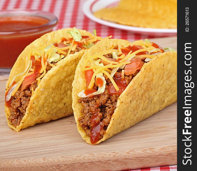 Two beef tacos with lettuce, tomato and sauce