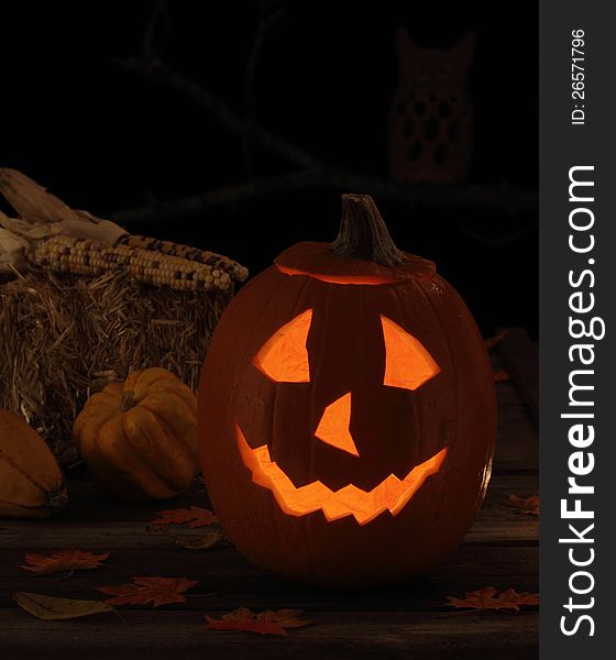 Smiling jack-o-lantern with autumn leaves on a wood deck