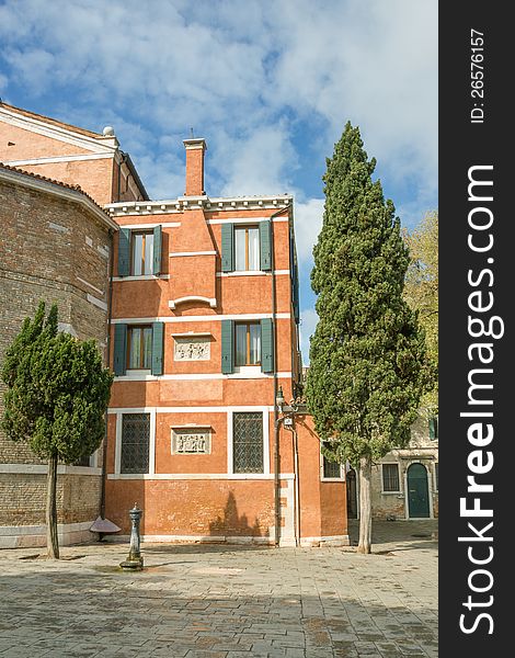 Square fragment of the Italian city with a facade of a building and trees