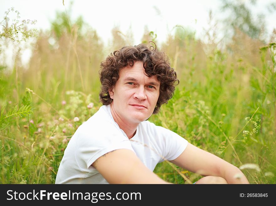 A young man sitting among flowering meadows. A young man sitting among flowering meadows.