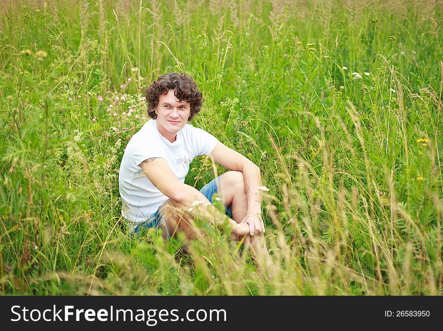 A young man sitting among flowering meadows. A young man sitting among flowering meadows.