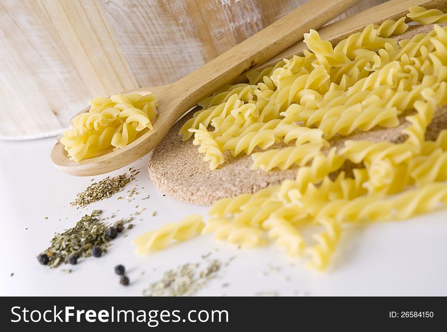 Raw pasta on spoon with spices for cooking