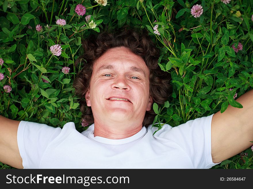 A young man laying on a flowering clover meadow, arms outstretched to the sides. A young man laying on a flowering clover meadow, arms outstretched to the sides.