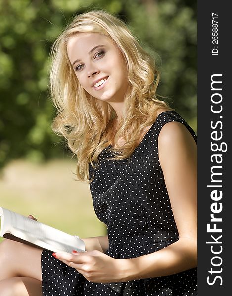 Young attracive blone woman reading book in park outdoor. Young attracive blone woman reading book in park outdoor