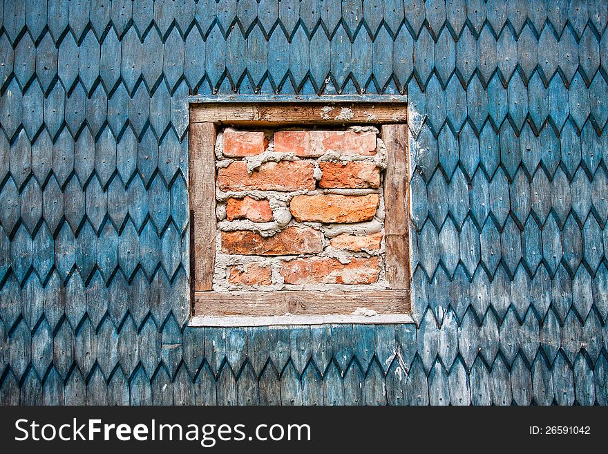 Wooden wall of the old house and window with bricks