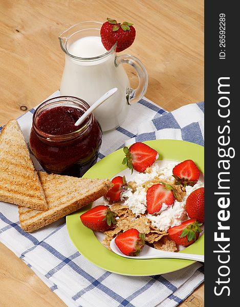 Light Breakfast of Toasts, Strawberries, Jam, Milk and Curds close up on wooden background