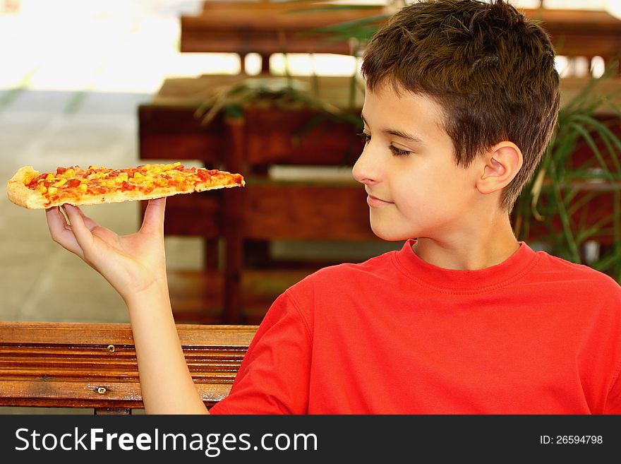A boy and a slice of pizza outdoor. A boy and a slice of pizza outdoor