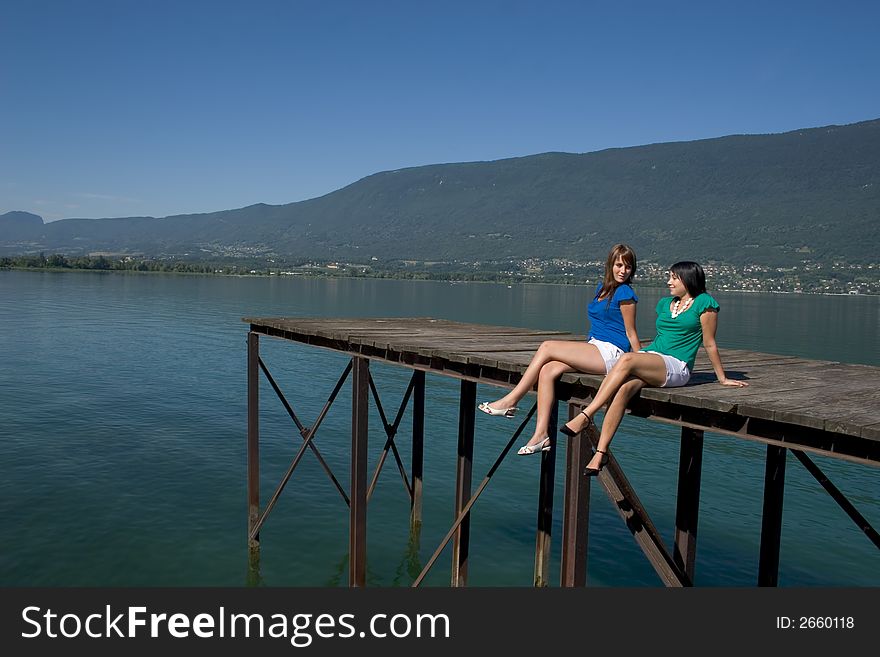 Young woman sitting on a pontoon at the edge of a lake. Young woman sitting on a pontoon at the edge of a lake