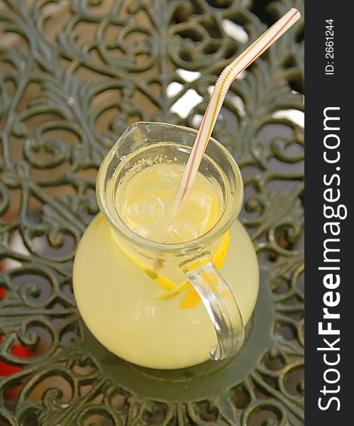 Upper view of a big cup with lemonade with a straw.The background represent an elegant coffee bar table.