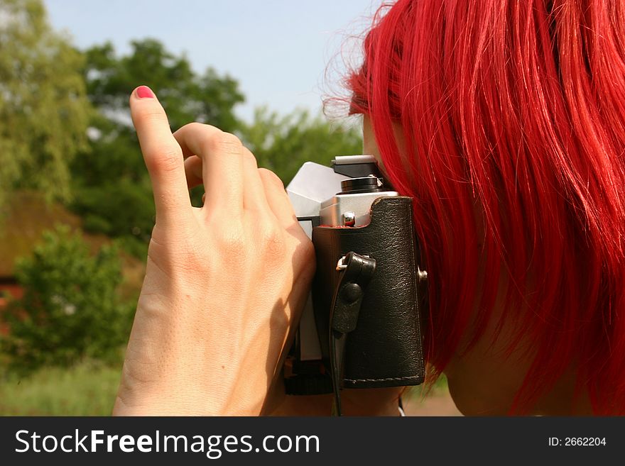 Pink fingernail on red haired photographer with camera taking pictures in nature. Pink fingernail on red haired photographer with camera taking pictures in nature