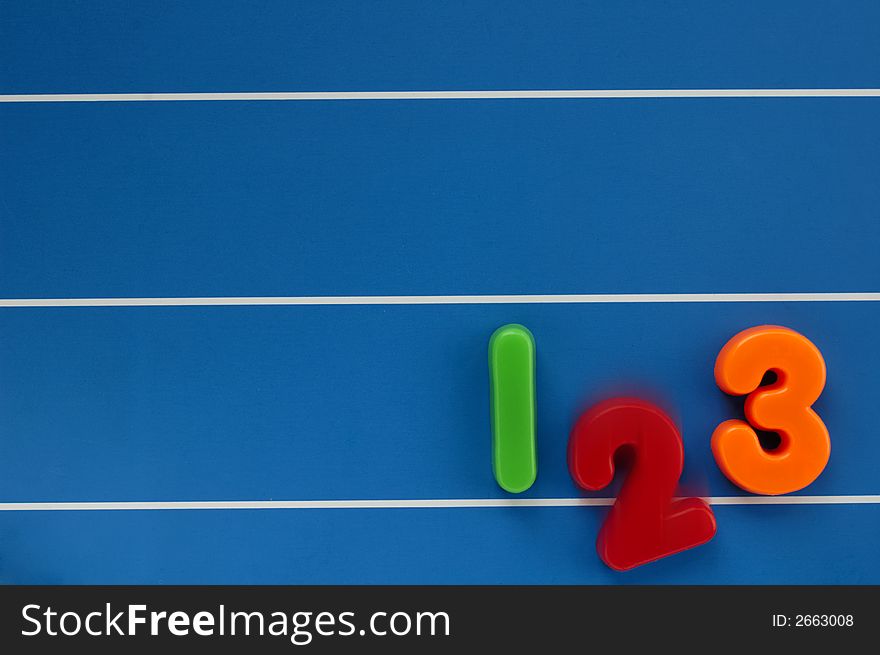 The numbers 1, 2 and 3 from a child's toy learning set, on a blue, lined background. The number 2 dropping out of the line, with motion blur. The numbers 1, 2 and 3 from a child's toy learning set, on a blue, lined background. The number 2 dropping out of the line, with motion blur.