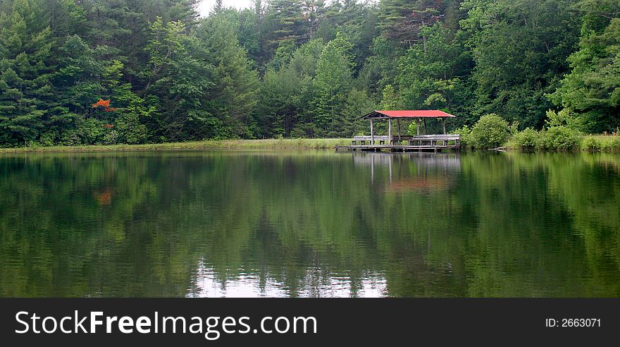 A rustic boat dock/pavilion on a lake surrounded by evergreens. A rustic boat dock/pavilion on a lake surrounded by evergreens