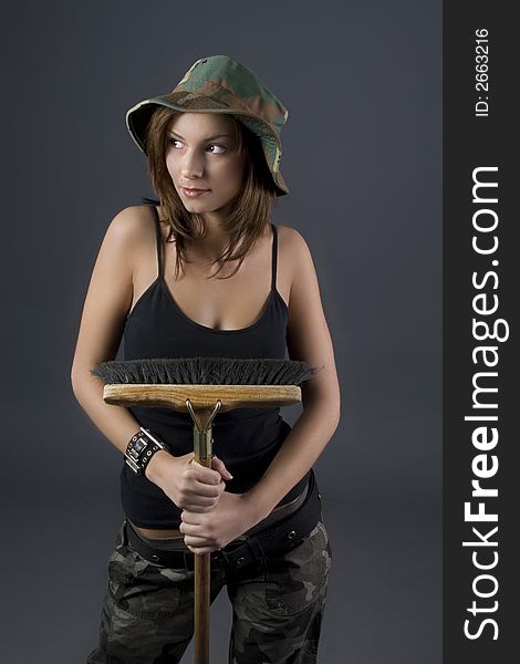 Attractive brunette military girl with a camouflage hat and black shirt holding broom. Attractive brunette military girl with a camouflage hat and black shirt holding broom