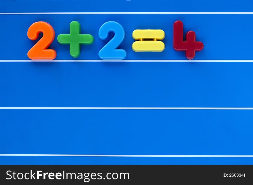 A simple sum, from a child's toy number set, placed on a blue, lined background. Space for text elsewhere in the image. A simple sum, from a child's toy number set, placed on a blue, lined background. Space for text elsewhere in the image.