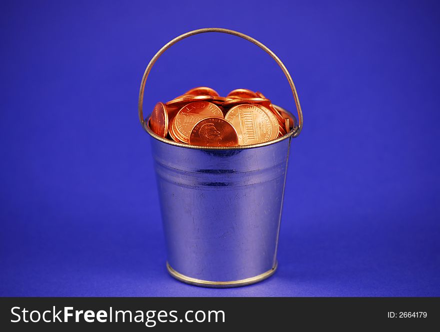 A metal bucket filled with shiny pennies. A metal bucket filled with shiny pennies