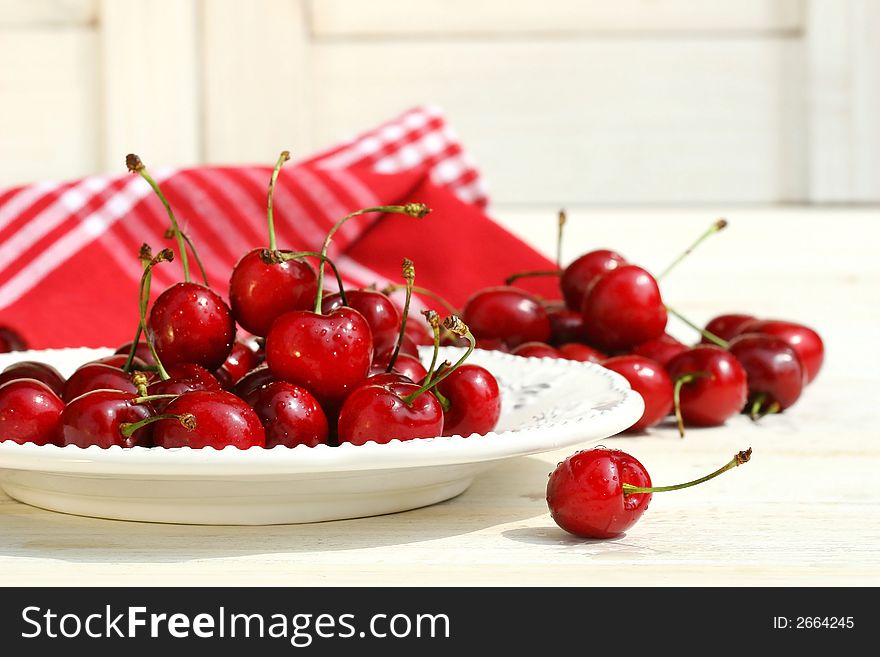 Red cherries on a plate with white shutters