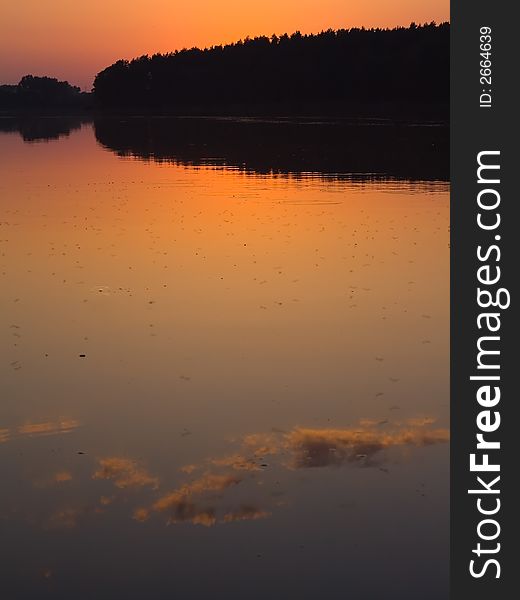 Sunset, quiet lake over blue-orange sky