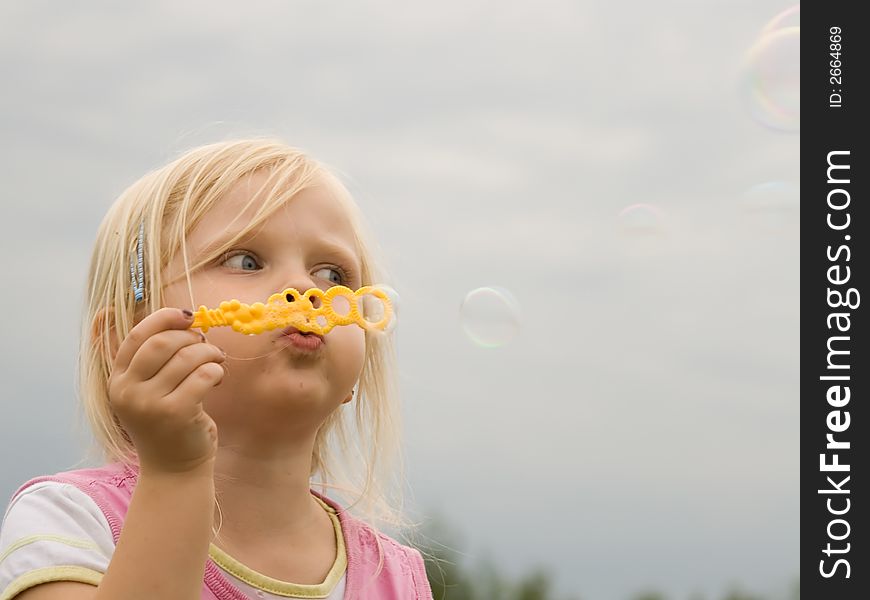 Young girl blowing soap bubbles. Young girl blowing soap bubbles