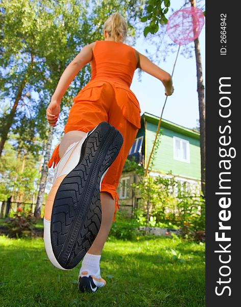 Girl with a butterfly net running on a meadow (focus on sole)