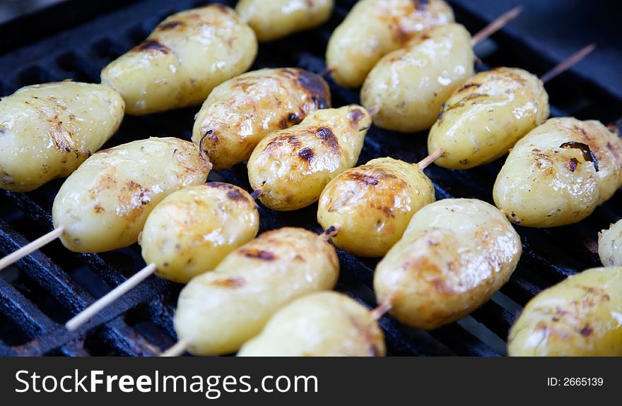 Grilled potatoes in wooden sticks, shallow focus
