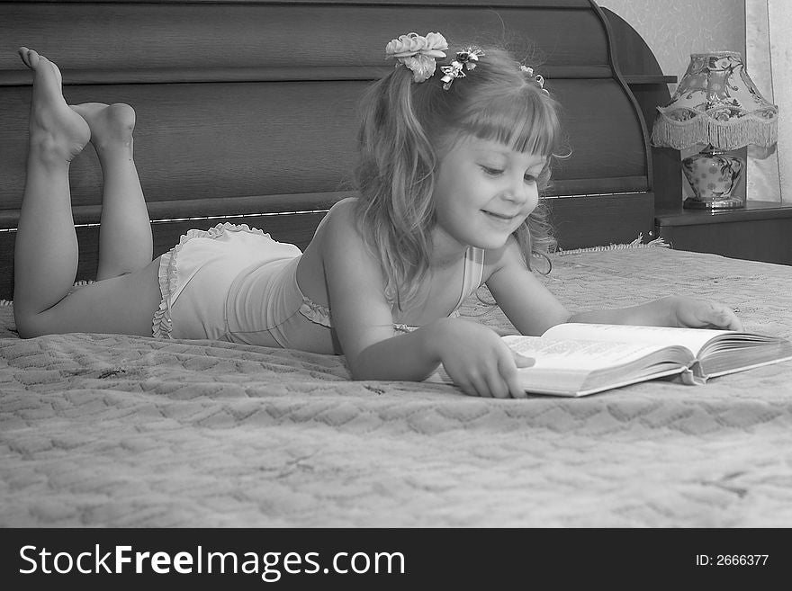 The girl reads the book on a bed