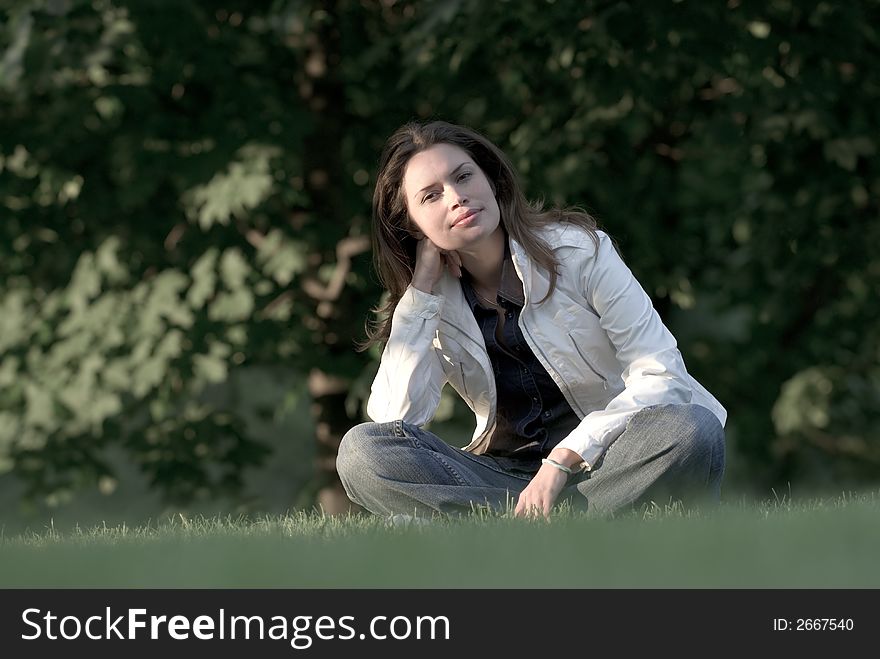 Pretty brunette relaxing on a fresh grass in a park. Pretty brunette relaxing on a fresh grass in a park