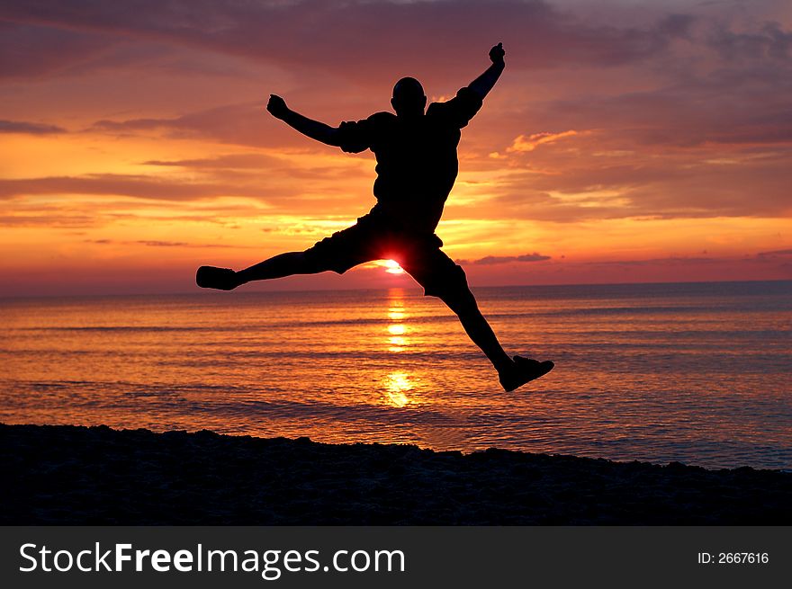 Man jumping on the beach at sunrise. Man jumping on the beach at sunrise