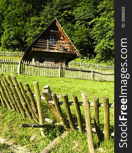 Old classic nice wooden fence and house in the summer meadow