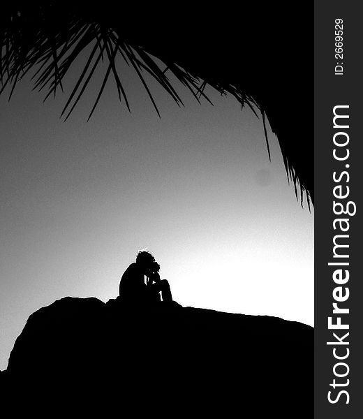 A person sits on boulders at Joshua Tree National Park to watch the sunset