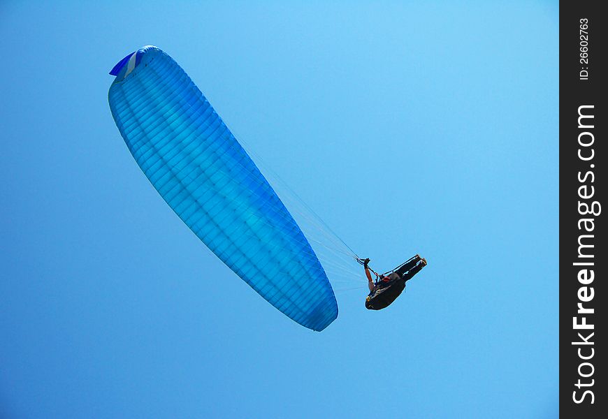 Man hovering, glides on a blue paraglider in the blue sky. Man hovering, glides on a blue paraglider in the blue sky