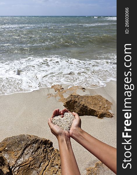 Mellow heart shaping female hands at the beach