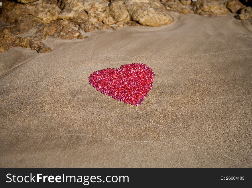 Glass balls laid in heart shape on sand